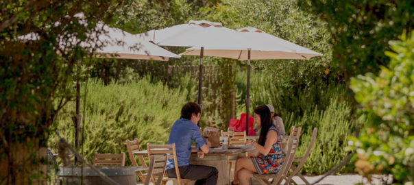 friends having lunch outside under umbrella