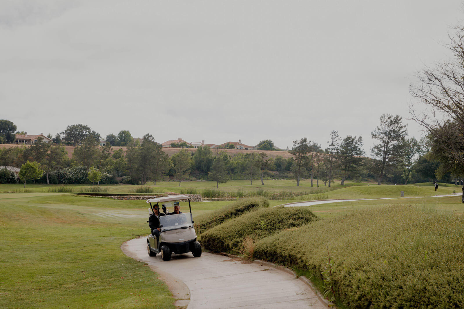 SYV Visitor Guide Two men in a golf cart driving on cart path on a golf course in the Santa Ynez Valley