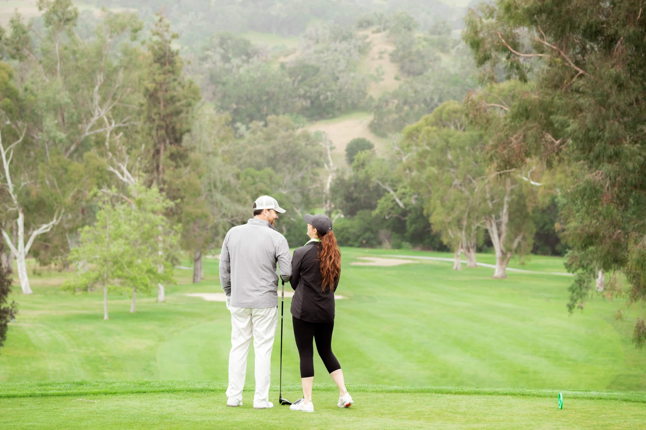 Man and woman standing on tee box at golf course